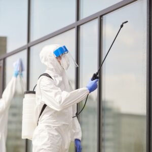 person in a hazmat suit spraying disinfectant